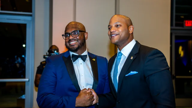 Two guests in formal suits greeting one another at a professional event