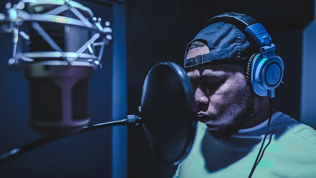 Recording artist in headphones concentrating beside a studio microphone