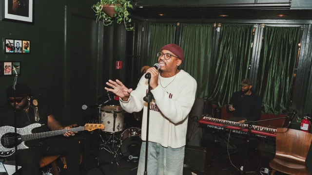 Vocalist in a white sweater performing with a live band