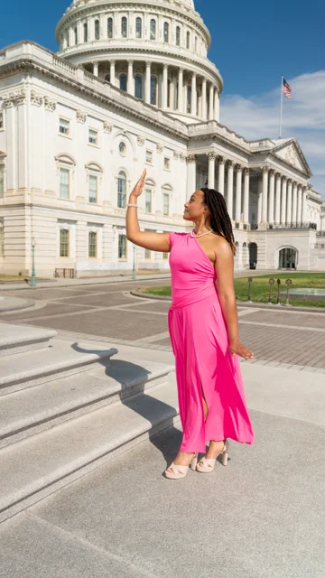 Full length portrait in a bright pink dress outside the Capitol