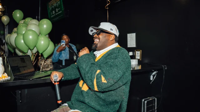 Guest in a green sweater celebrating beside green balloons