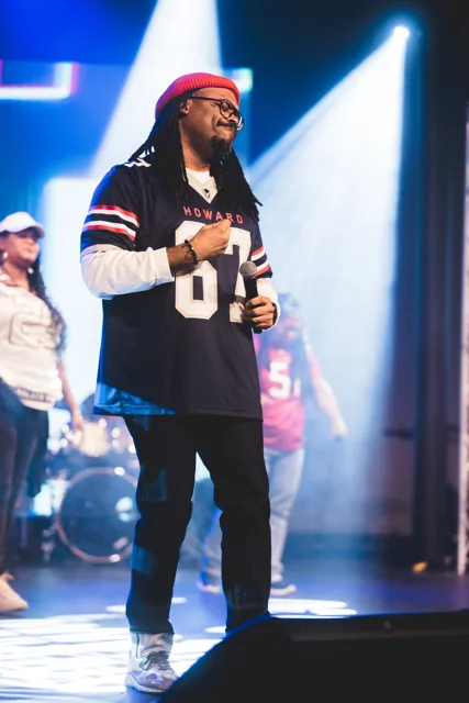 Full length concert photograph of a performer in a red cap