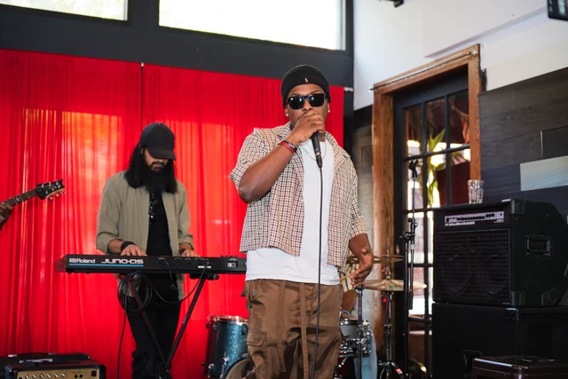 Vocalist in sunglasses performing beside a keyboardist at Out the Box