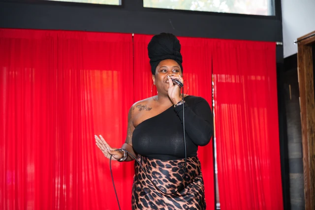 Singer in a black top and leopard print skirt performing at Out the Box