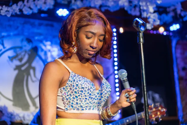 Singer holding a microphone beneath blue stage lighting