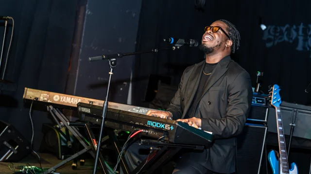 Keyboardist singing into a microphone during a live performance