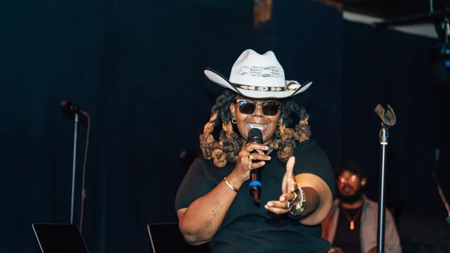 Vocalist in a white cowboy hat pointing toward the audience