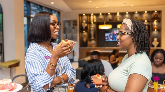Two guests sharing a conversation over colorful drinks