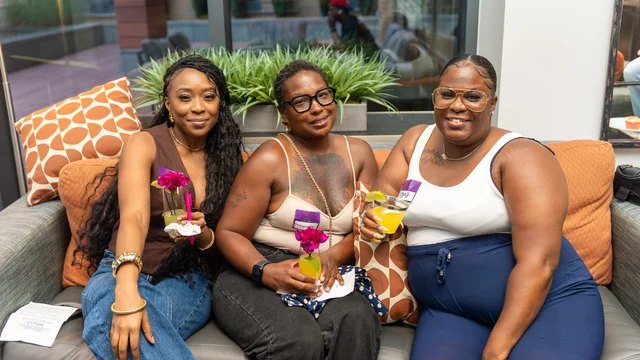 Three guests smiling together with drinks at a social gathering